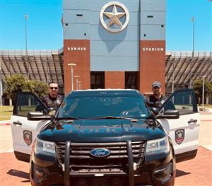 2 officers standing with police car